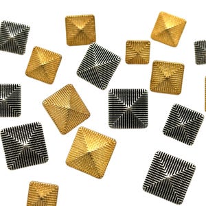 May include: A collection of gold and silver pyramid-shaped buttons. The buttons are scattered on a white background.