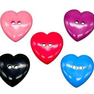 May include: Five heart-shaped buttons in different colours: pink, red, purple, black, and blue. Each button has two holes.