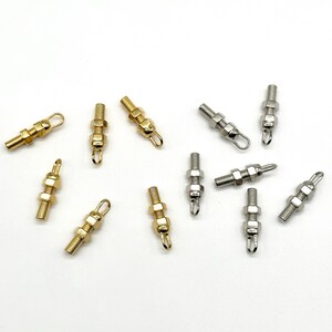 May include: A collection of gold and silver metal screw-on charms with a loop at the top. The charms are in the shape of a nut and bolt.