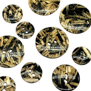 May include: Assortment of ten round, two-hole buttons with a black background and a pattern of tan and brown straw-like material.