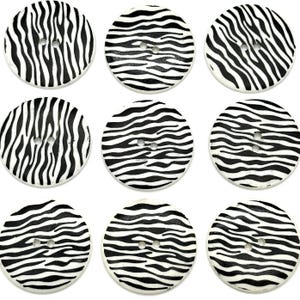 Puede incluir: Nueve botones de madera con estampado de cebra en blanco y negro. Cada botón tiene dos agujeros.