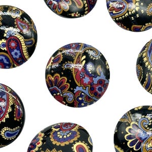 Op de afbeelding: Een set van acht ronde, zwarte knopen met een paisley-patroon in tinten rood, blauw, goud en wit.