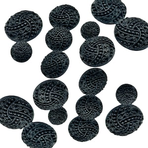 May include: A collection of black buttons with intricate designs. The buttons are round and have a raised, textured surface.