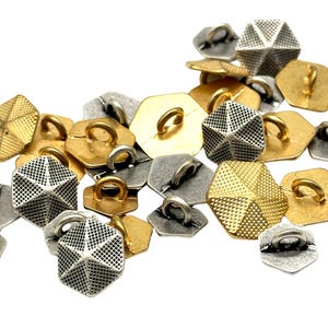 May include: A collection of gold and silver hexagonal buttons with a geometric design. The buttons have a loop on the top for sewing.