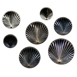 Könnte beinhalten: Satz von sieben dekorativen Wandbehängen in Form einer Muschel. Die Muscheln sind aus Metall und haben eine silberne und schwarze Oberfläche.