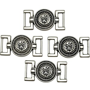 Może przedstawiać: Pięć srebrnych metalowych klamer do paska. Każda klamra ma okrągły wzór z głową lwa pośrodku, otoczoną obramowaniem w kształcie liny. Klamry mają prostokątne pętle po każdej stronie do mocowania do paska lub paska.