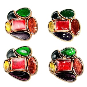 Puede incluir: Cuatro pendientes de clip coloridos. Cada pendiente presenta un engaste dorado con una piedra rectangular roja central, rodeada de piedras verdes, amarillas, naranjas, negras y moradas. Los pendientes tienen un diseño geométrico abstracto.