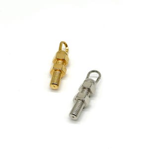 May include: Two metal charms in the shape of stacked nuts and bolts. One charm is gold and the other is silver.