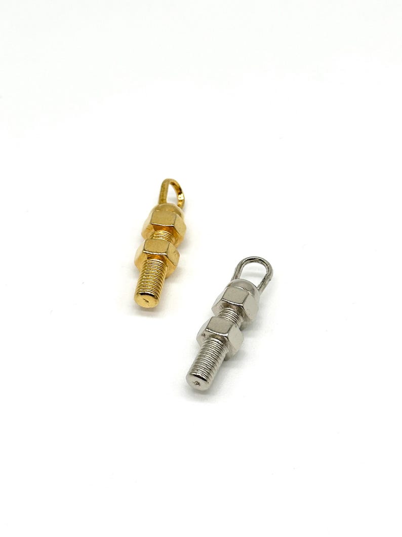 May include: Two metal charms in the shape of stacked nuts and bolts. One charm is gold and the other is silver.
