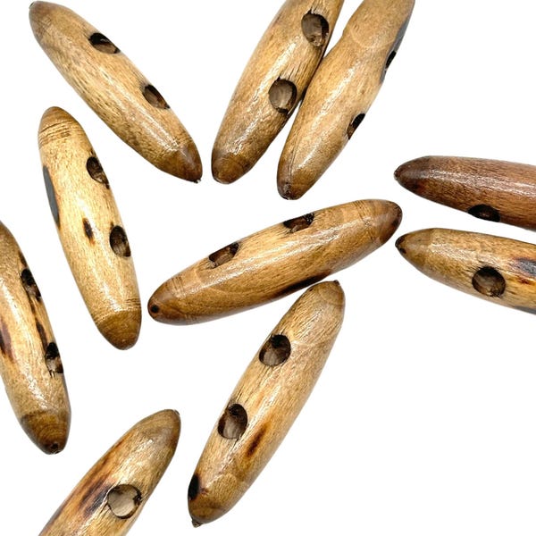 May include: A group of ten wooden toggle buttons with two holes each. The buttons are a light brown color and have a natural wood grain.