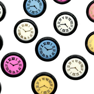 May include: Assortment of ten miniature clock faces with black rims and Roman numeral markings. The clock faces are in various colors, including pink, blue, white, and yellow.