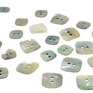 May include: A collection of 18 iridescent, mother-of-pearl buttons in a square shape with two holes each. The buttons are scattered on a white background.