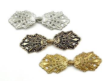 May include: Three pairs of decorative metal clasps in silver, gold, and brass finishes. Each clasp features a delicate, ornate design with a floral motif.