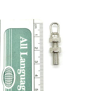 May include: A silver metal hook with a threaded shaft and two nuts. The hook is approximately 3 cm long.