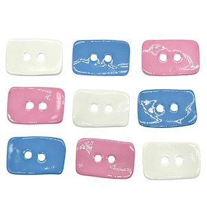 May include: Nine rectangular buttons in white, light blue, and pink. Each button has two holes and a slightly textured surface.