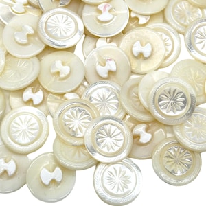 Peut inclure: Une collection de boutons en nacre blanche avec différents motifs, dont un motif en étoile et un motif simple à deux trous.