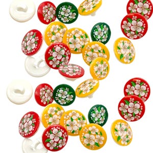 May include: Assortment of colourful buttons with a floral design. The buttons are red, yellow, and green with white flowers.