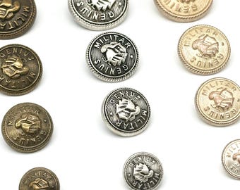 May include: A collection of 10 metal buttons with a raised design of two hands clasped together. The buttons are in various shades of gold, silver, and bronze. The text "MILITAR GENIUS" is engraved on each button.