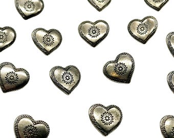 May include: A collection of silver heart-shaped charms with a decorative floral design in the center.