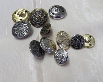 May include: Assortment of metal buttons with a crest design. The buttons are in various shades of gold, silver, and black.