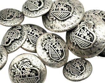 May include: A set of silver-toned buttons with a raised design of a coat of arms. The buttons have a textured surface and are perfect for adding a touch of elegance to any garment.