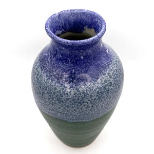 May include: A handcrafted ceramic vase with a speckled blue and green glaze. The vase has a rounded body and a flared rim. The top is a deep blue, transitioning to a speckled blue-green, and ending with a solid green base. A decorative home accent.