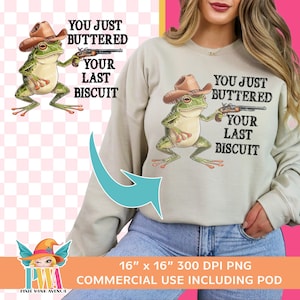 May include: A light beige sweatshirt with a green frog wearing a cowboy hat and holding a gun. The text "You just buttered your last biscuit" is printed on the sweatshirt.