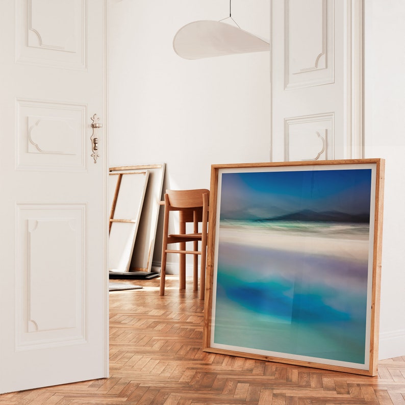 May include: A framed photograph of a seascape with a blue sky, white sand, and turquoise water. The frame is made of wood and has a light brown finish.