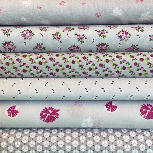 Könnte beinhalten: Fünf Stoffrollen mit verschiedenen Mustern. Die oberste Rolle ist ein hellgrauer Stoff mit einem kleinen Blumenmuster. Die zweite Rolle ist ein hellgrauer Stoff mit einem kleinen Blumenmuster in Rosa- und Lilatönen. Die dritte Rolle ist ein hellgrauer Stoff mit einem kleinen weißen Punktmuster. Die vierte Rolle ist ein hellgrauer Stoff mit einem größeren rosafarbenen Blumenmuster. Die unterste Rolle ist ein graues und weißes geometrisches Muster.