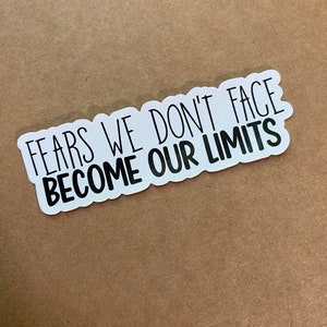 May include: White sticker with black text that reads "Fears we don't face become our limits".