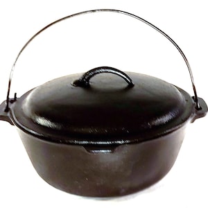 May include: A black cast iron Dutch oven with a lid and a wire handle. The oven is on a white background.