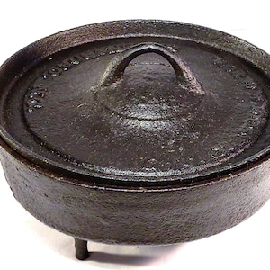 May include: A cast iron pot with a lid and three legs. The pot has a handle on the lid and is marked "Wagner Ware"