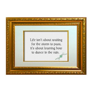 May include: A framed inspirational quote in a gold frame. The quote reads: "Life isn't about waiting for the storm to pass, it's about learning how to dance in the rain."