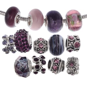 May include: A set of 12 purple and pink charm beads for jewelry making. The beads are made of glass, metal, and crystal. Some beads have a floral design, while others have a geometric design.