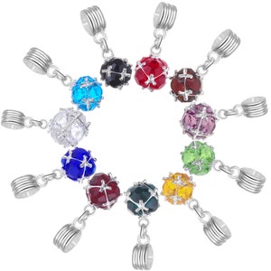 May include: Set of 12 colourful crystal ball hair tie charms with silver metal caps. Each charm features a crystal ball with a cross design.