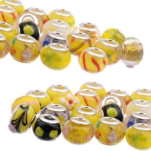 May include: A collection of yellow glass beads with various patterns and designs. The beads have silver accents and are perfect for jewelry making.