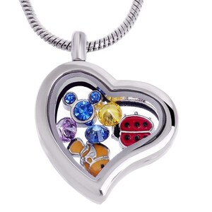 Peut inclure: Un collier avec un pendentif en forme de cœur argenté et un insert en verre transparent. Le pendentif contient des breloques colorées, dont une coccinelle, un poisson, une tête de Mickey Mouse et divers cristaux.