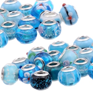 May include: A collection of blue glass beads with silver accents. The beads have various designs, including swirls, glitter, and flowers.