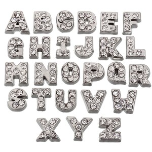 May include: A set of 26 silver-toned alphabet letter charms, each letter is encrusted with clear rhinestones.