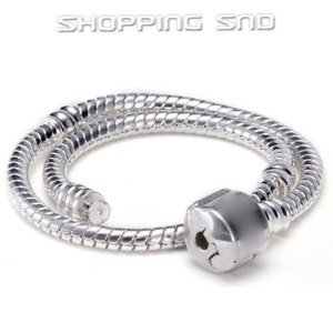 Puede incluir: Un brazalete de cadena de serpiente plateado con un cierre. El brazalete está hecho de una serie de pequeños eslabones interconectados que se asemejan a las escamas de una serpiente.