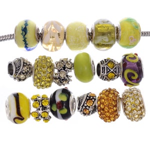Peut inclure: Un ensemble de perles en verre et en métal colorées avec différents motifs, notamment des volutes, des motifs géométriques et des strass. Les perles sont jaunes, vertes, violettes et orange.