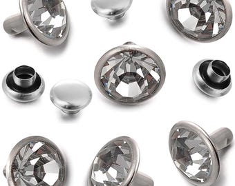 May include: A collection of silver-toned metal rivets and studs with clear, faceted crystal-like centers. The rivets have a post for attachment, while the studs are flat. The crystals reflect light, creating a sparkling effect. Ideal for leathercraft or adding embellishments.