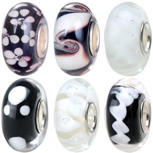 May include: Six glass beads with silver metal accents. The beads have various patterns including polka dots, swirls, and flowers. The beads are black and white.