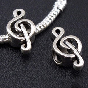 Puede incluir: Dos abalorios de plata con forma de clave de sol. Los abalorios están diseñados para usarse en una pulsera de abalorios.