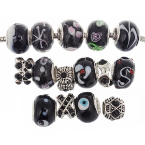 May include: A set of black and silver charm beads for a bracelet. The beads feature various designs, including flowers, eyes, and geometric patterns.