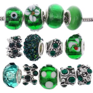 May include: A set of 12 green and silver charm beads for a bracelet. The beads are made of glass, metal, and rhinestones. Some beads have a flower design, others have polka dots, and others have a crystal-like appearance.