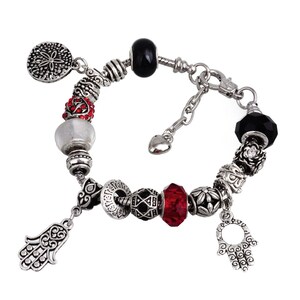 May include: Silver charm bracelet with red, black, and white beads, including a hamsa hand charm and a star of David charm.
