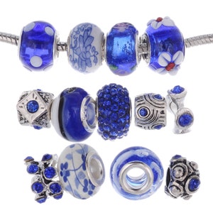 May include: A set of blue and white charm beads for a bracelet or necklace. The beads are made of glass, ceramic, and metal. Some beads feature a floral design, while others have a sparkly blue finish.