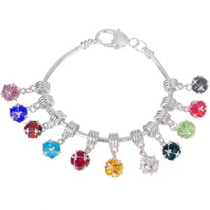 May include: A silver charm bracelet with a heart-shaped clasp and multiple dangling charms. Each charm is a small sphere with a different coloured crystal inside. The crystals are pink, blue, red, turquoise, red, yellow, clear, and green.
