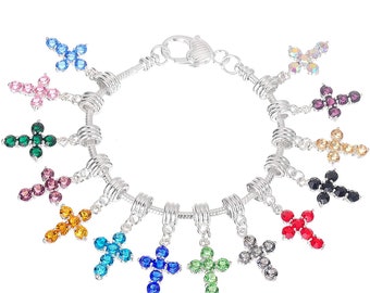 May include: A silver charm bracelet featuring a selection of colourful cross charms. Each charm is adorned with a different coloured crystal, including red, blue, green, purple and yellow.